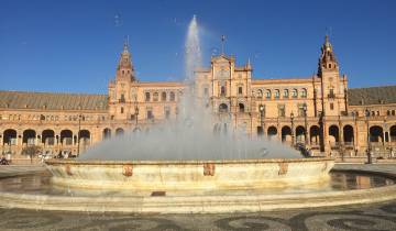 Fountain in front of Spain Square with a historical building in the background.