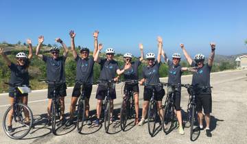 Group of cyclists posing with their bikes on a sunny day.
