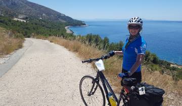 Woman posing with a bicycle overlooking the sea.
