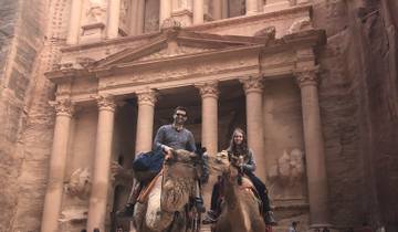 People riding camels in front of a historic building