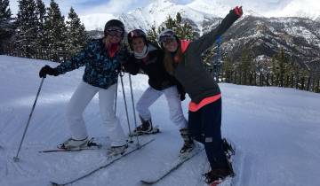 Three people posing with skis on a snowy mountain.