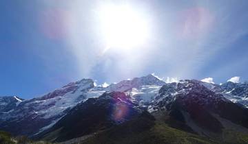 Sun shining over snowy mountain peaks.