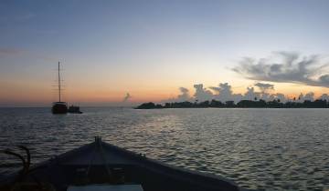 Silhouette of boats at sunset on the ocean.