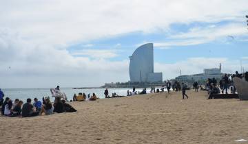 People enjoying a beach day with a futuristic building in the background.