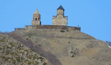 Ancient church complex on hilltop against a clear blue sky.
