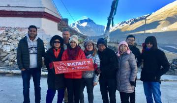 Group holding an Everest banner with mountains in the background.
