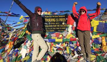 Two people celebrating at Thorong La Pass with prayer flags.