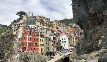 Colorful houses built on a cliffside, with a large rock face and blue sky.