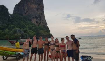 Group of people posing on a beach with a cliff.