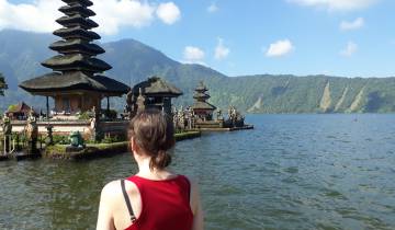 Woman looking at Pura Ulun Danu Beratan temple by the lakeside.