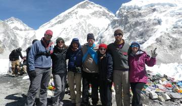 Group of trekkers posing with snow-capped mountains in the background.