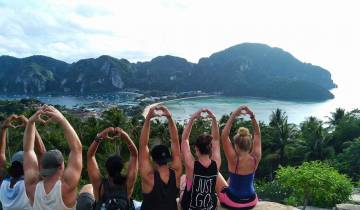Group posing at a viewpoint overlooking tropical landscape.