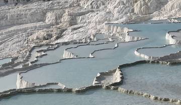 Beautiful travertine terraces filled with water under a clear sky.