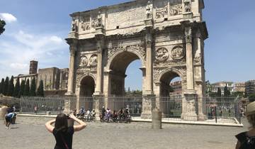 Historic triumphal arch with tourists standing and taking photographs.