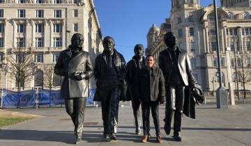 Person posing with famous statues in an urban setting.