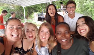 Group of people smiling and posing closely together under a canopy.