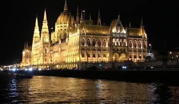 A beautifully lit building at night reflected in the river.