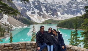 Family posing with a stunning blue lake and mountains in the background.