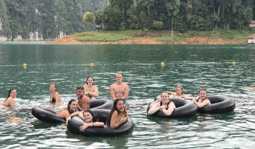 Group of people enjoying floating in inner tubes on a lake.