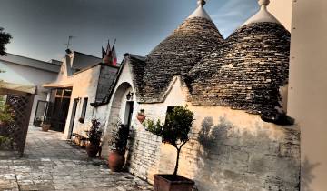 Traditional trulli with stone cone roofs in a sunlit setting.