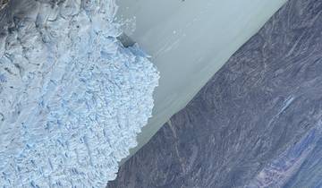 Aerial view of a glacier meeting a lake.