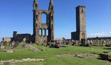 Historic cathedral ruins with cemetery and tourists.