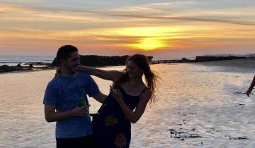 Couple standing on the beach during sunset.