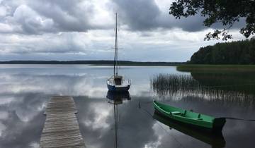 A dock with sailboats on a calm lake under cloudy skies.