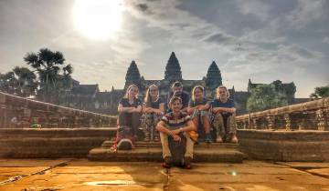 People posing in front of Angkor Wat temple at sunrise