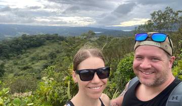 Couple posing with a panoramic view of forested hills.