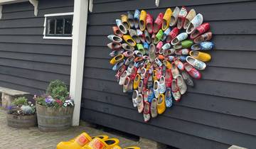 Wall with a variety of colorful wooden clogs displayed.