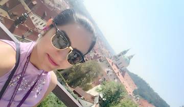Woman with sunglasses taking a selfie with a city skyline.