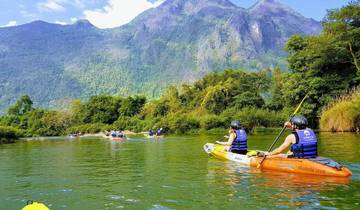 People kayaking in a river surrounded by mountains.