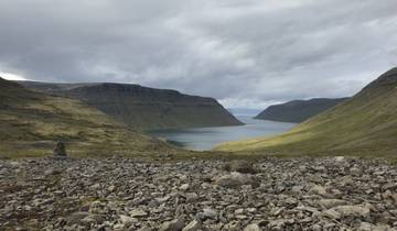 Majestic fjord landscape with rocky ground and cloudy sky.