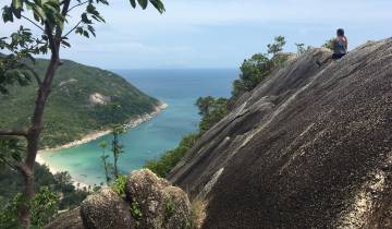 A person sitting on a rocky outlook above a bay.