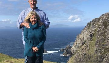 A couple posing against a backdrop of cliffs and sea.