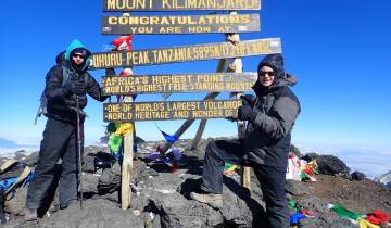 Two people posing at the summit with signs.
