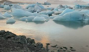 Icebergs floating in calm water with reflections.