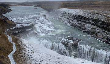 Waterfall cascading down snow-covered cliffs.
