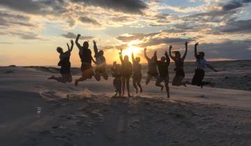 Group jumping in the air on a beach at sunset.