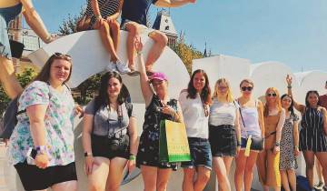 Group of people posing in front of a large white sign in an urban area.