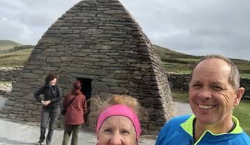 Couple posing in front of a stone beehive house.