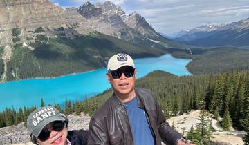 Two people with a stunning view of a turquoise lake and mountains.