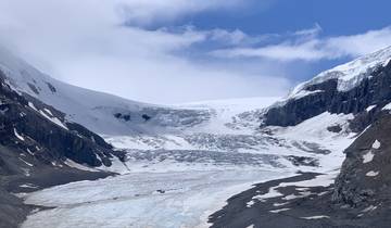 Snow-covered glacier nestled between mountain peaks.