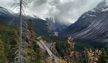 Mountain pass with a road winding through it under cloudy skies.