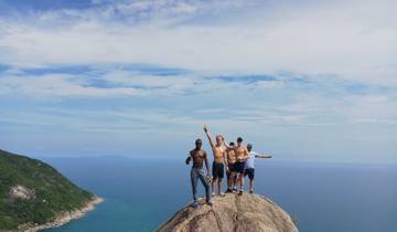 A group of people standing on a rock with a scenic ocean backdrop.