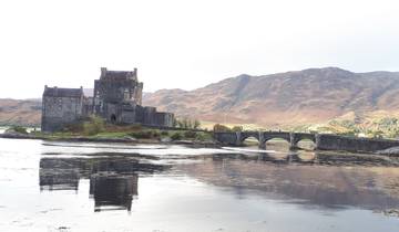 A scenic castle on a loch with mountains behind.