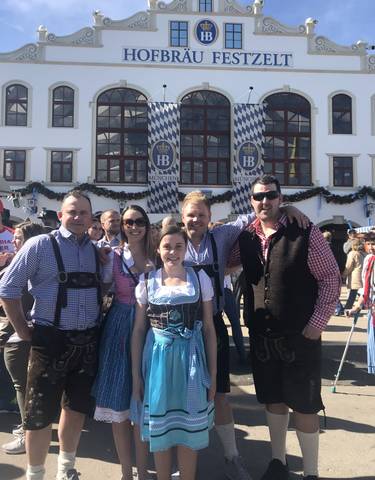 Five people in traditional clothing at a festival.