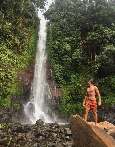 A man standing next to a waterfall.