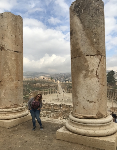 View of ancient ruins framed by large columns with a person standing nearby.